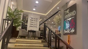 A staircase leading to a bar and cafe area with a neon sign indicating the location. - Atlas Hotels (Cairo)