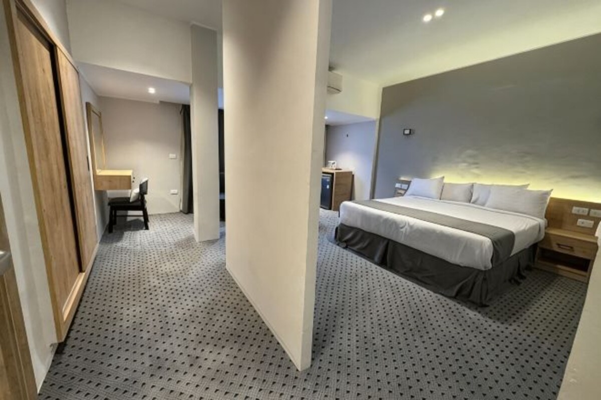 Quarto de hotel com cama, mesa de cabeceira e escrivaninha com cadeira.