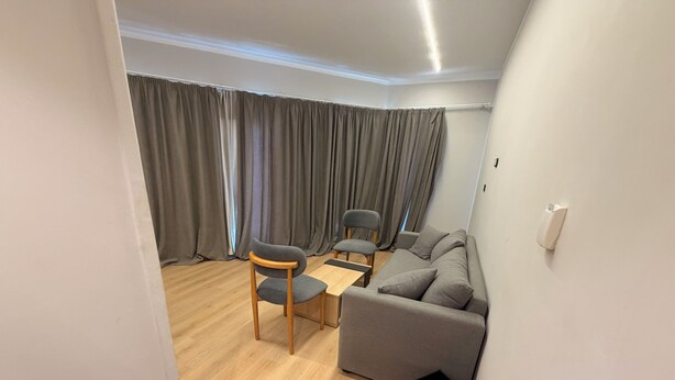 A modern living room with a sofa, two chairs, a small table, and a black trash bin. - Atlas Hotels (Cairo)