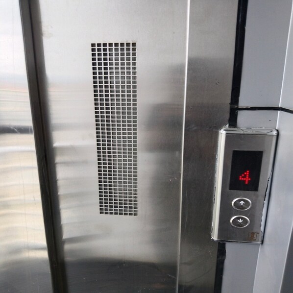 A metallic elevator interior with a digital display showing the number 4 and a control panel with directional buttons.