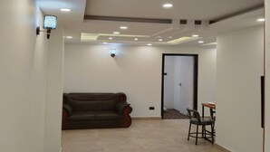 Habitació àmplia amb un sofà de pell marró, una taula de dinar amb cadires, il·luminació encastada al sostre i una porta que condueix a una altra zona.