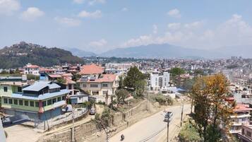 A residential area with houses, a road, and a hilly landscape in the background.