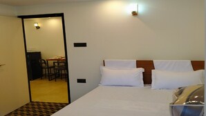 Una habitació d'hotel amb un llit gran, una taula i una cadira.