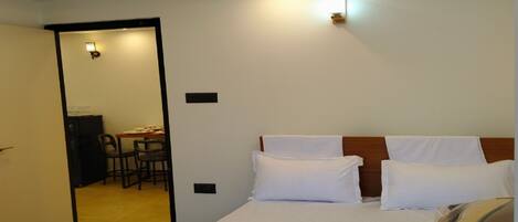 A hotel room with a large bed, a desk, and a chair.