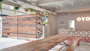 Ein modernes Interieur mit einer langen Holzbank, hängenden Pflanzen und einer Wand mit dem Schriftzug 'OYO'.