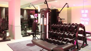 A gym with exercise equipment, a bench, and a rack of dumbbells.