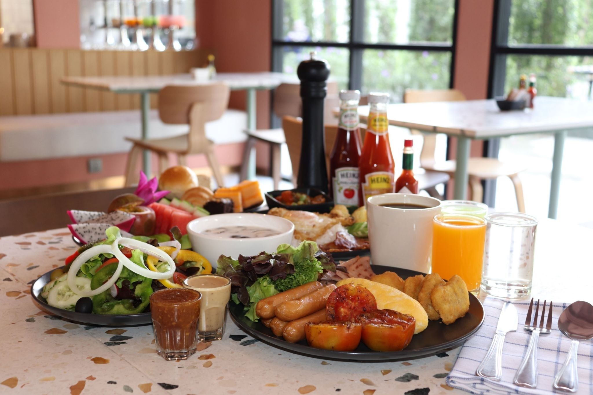 A breakfast buffet with various dishes, condiments, and beverages.