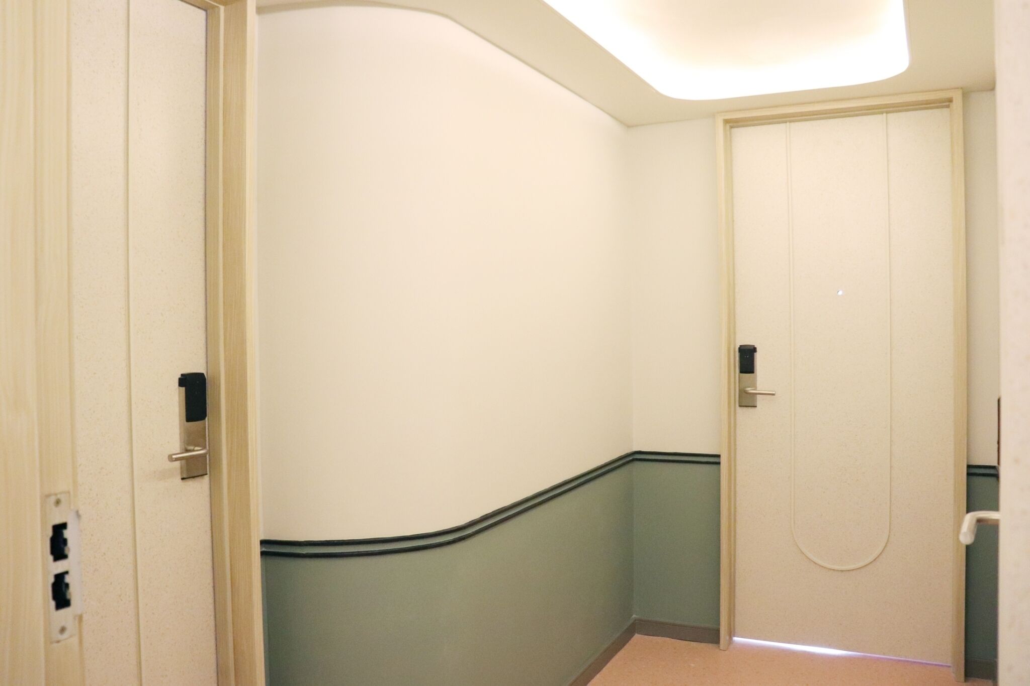 A hallway with a door, a light fixture, and a wall switch.