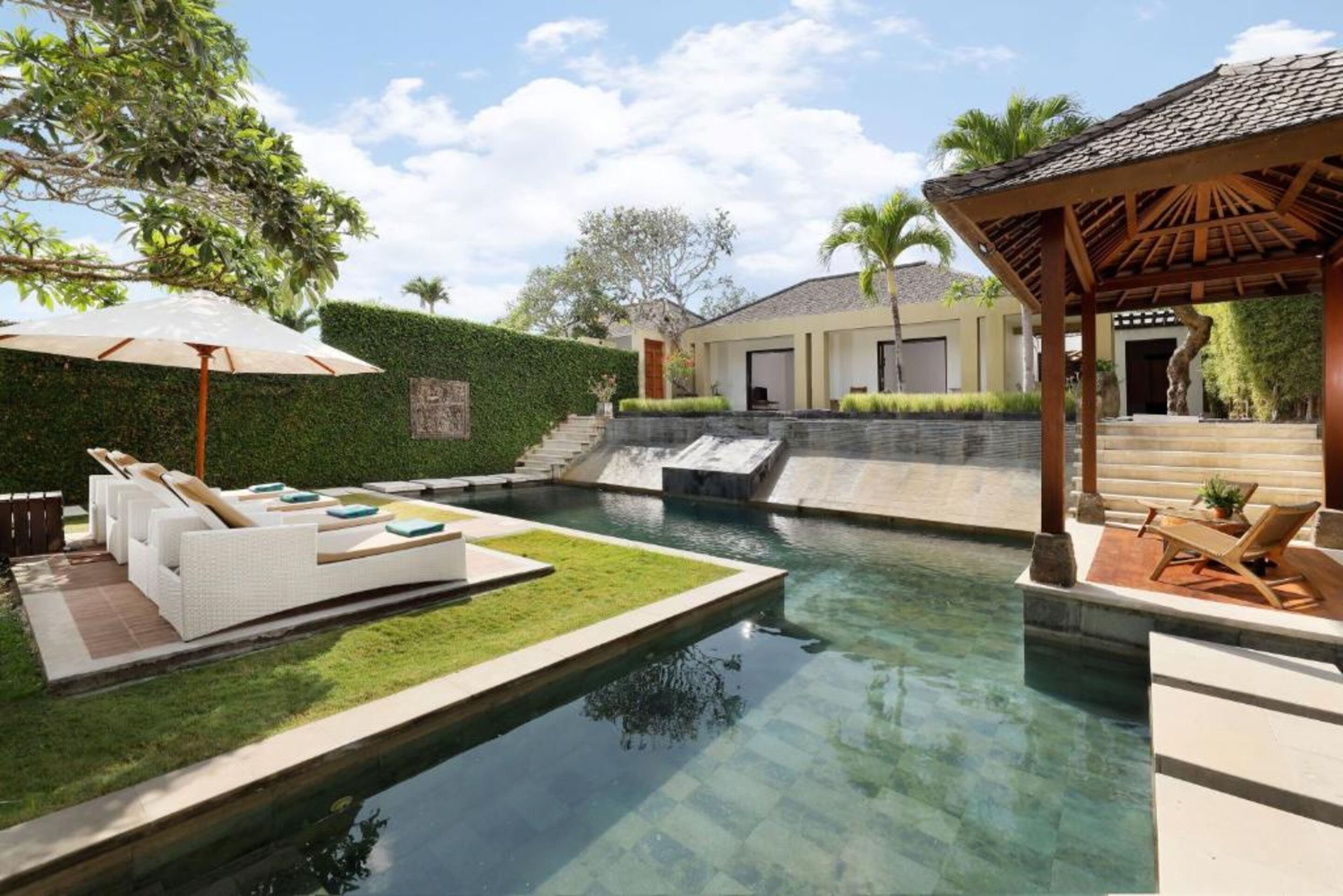 A swimming pool with a sun lounger and a covered seating area.