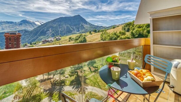 Ein Balkon mit Tisch, Stühlen und Bergblick.