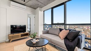 A modern living room with a large window, a flat-screen TV, a sofa, and a coffee table. - NEW! Stature Style Southbank! (Southbank)