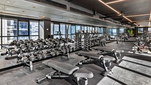 A modern gym with various exercise equipment, large windows, and a high ceiling. - NEW! Stature Style Southbank! (Southbank)