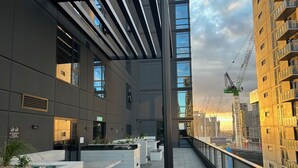 A modern building with a covered outdoor area, large windows, and a view of the city skyline. - Spectacular Views, Comfort, Convenience. Gym, Pool, Rooftop, Tram, walk to Crown (Southbank)