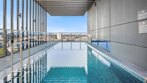A rooftop infinity pool with a city view, metal railings, and a 'No Lifeguard on Duty' sign. - Spectacular Views, Comfort, Convenience. Gym, Pool, Rooftop, Tram, walk to Crown (Southbank)