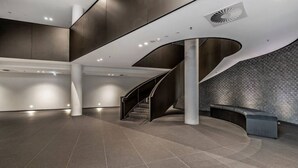 A spacious lobby with a curved staircase, a seating area, and a patterned wall. - The Park House City Retreat on the Yarra River (Abbotsford)