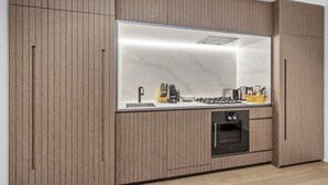 A modern kitchen with wood paneling, a built-in stove, and a large window. - The Park House City Retreat on the Yarra River (Abbotsford)