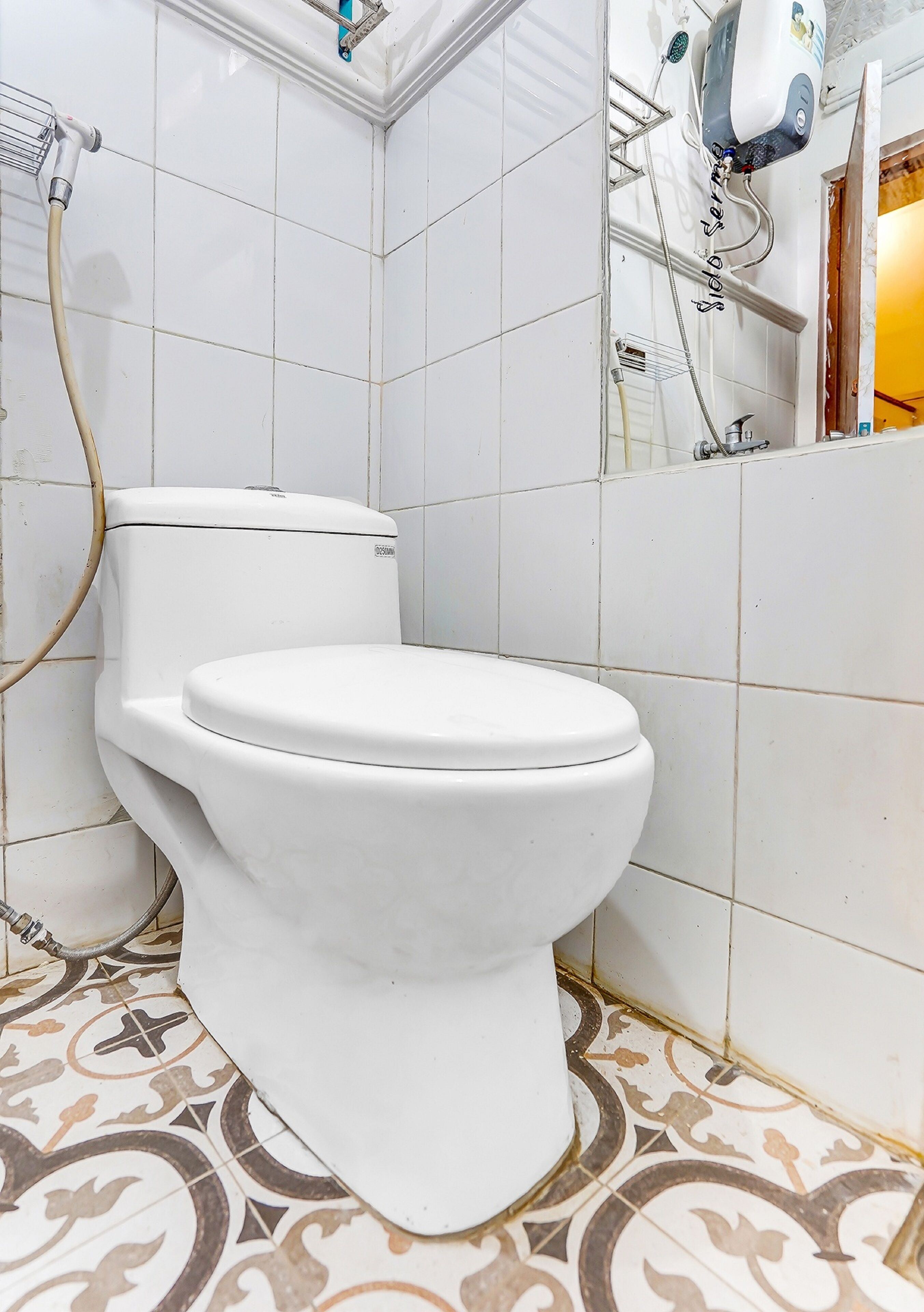 A bathroom with a white toilet, a showerhead, and a tiled floor.