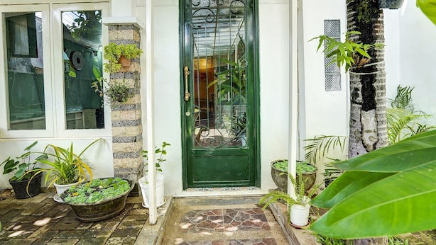 A green door with a metal gate, potted plants, and a stone-tiled entrance. - OYO Life 2929 Kost Sofie Syariah (Surabaya)