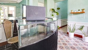 A reception desk with a laptop, wicker chairs, and potted plants. - OYO Life 2929 Kost Sofie Syariah (Surabaya)