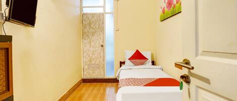 Una habitación de hotel con una cama, televisión, aire acondicionado y una puerta con manija.
