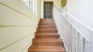 A staircase with wooden steps and white railings leading to a dark door. - OYO Life 2929 Kost Sofie Syariah (Surabaya)