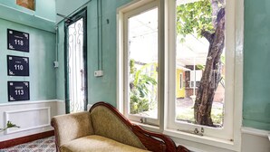 A room with a sofa, a door with a number sign, and a window with a view of the outside. - OYO Life 2929 Kost Sofie Syariah (Surabaya)