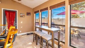 A dining area with a table and chairs, large windows, and a ceiling fan. - Flagstaff Family Retreat~Game Room~Hot Tubs (Flagstaff)