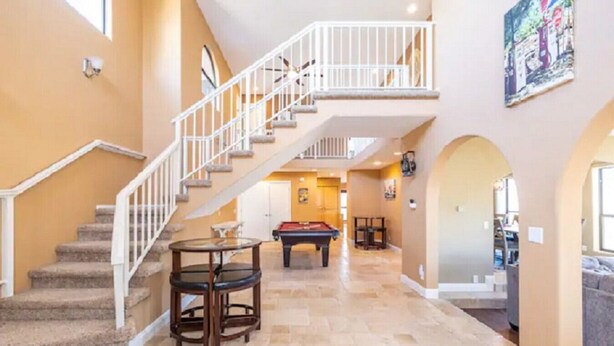 A spacious indoor area with a staircase leading to an upper level, a pool table, and a billiards table. - Flagstaff Family Retreat~Game Room~Hot Tubs (Flagstaff)