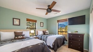 A bedroom with two beds, a ceiling fan, a dresser, and a TV on the wall. - Flagstaff Family Retreat~Game Room~Hot Tubs (Flagstaff)