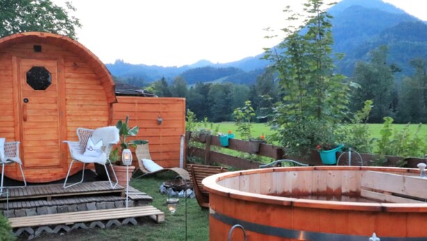 Eine Holzhütte mit einem runden Whirlpool, einer Terrasse mit Stühlen und einem Schild, das einen privaten Bereich kennzeichnet.