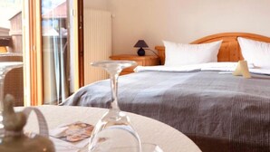Ein Hotelzimmer mit Bett, Nachttisch, Lampe und Blick durch eine Glastür.