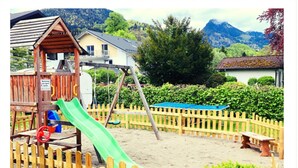 Ein Spielplatz mit Rutsche, Holzzaun und Bank.