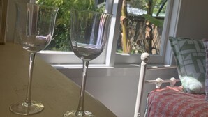 To vinglas af gennemsigtigt glas på et træbord nær et vindue med udsigt til en have.
