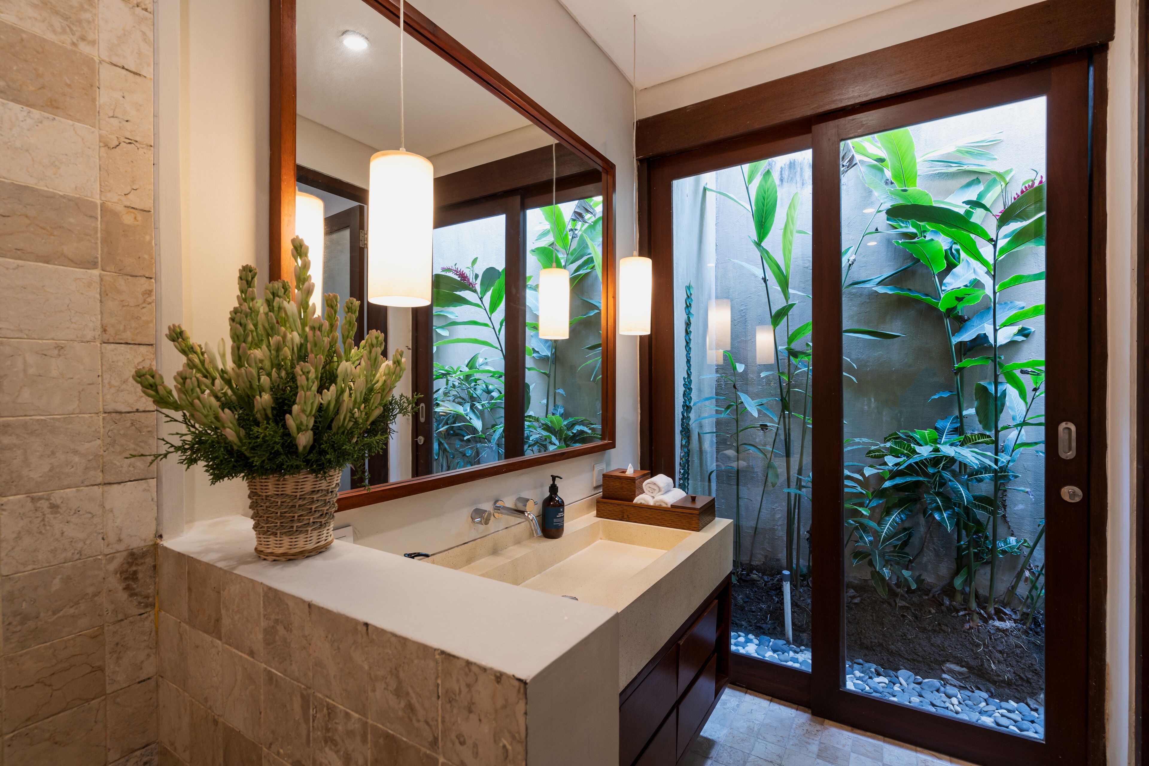 Un baño con un espejo grande, un lavabo y una planta en maceta.