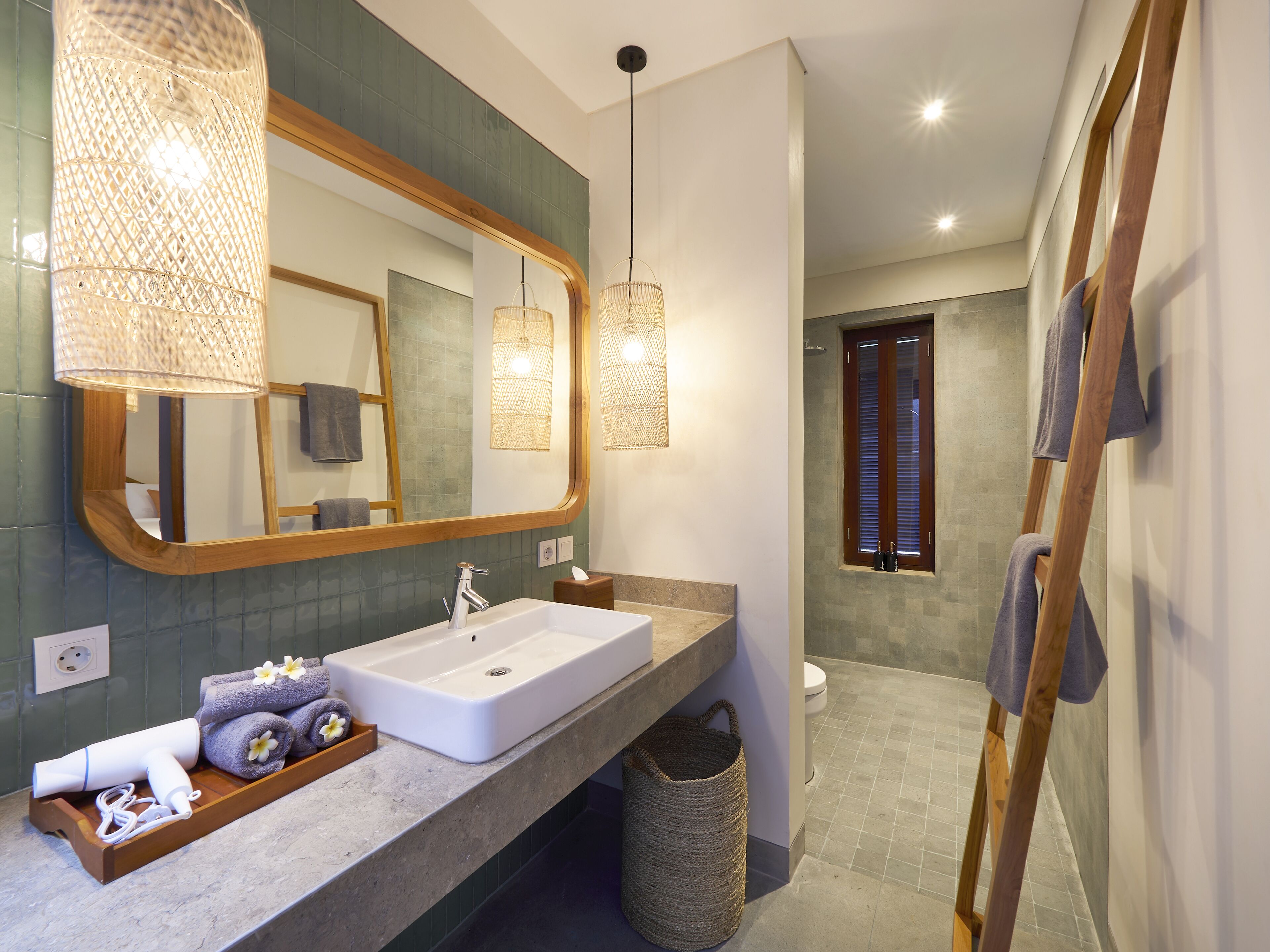Un baño moderno con un espejo grande, un lavamanos blanco y una zona de ducha.