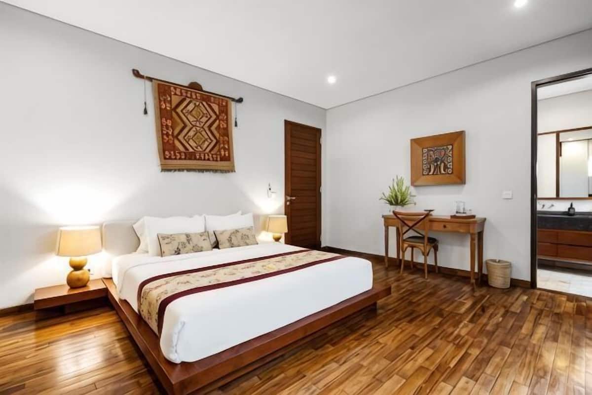Un dormitorio con una cama grande, mesitas de noche, un escritorio y una silla.