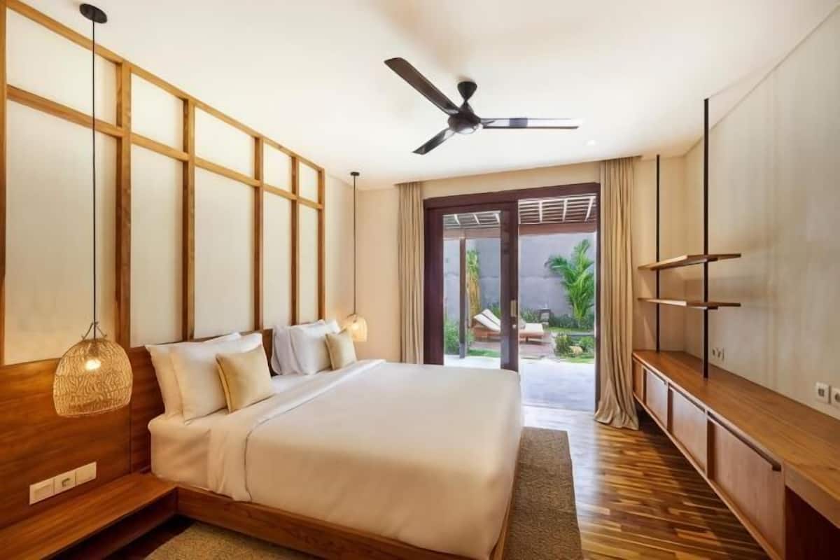 Un dormitorio con cama, ventilador de techo, televisión y vistas al exterior.