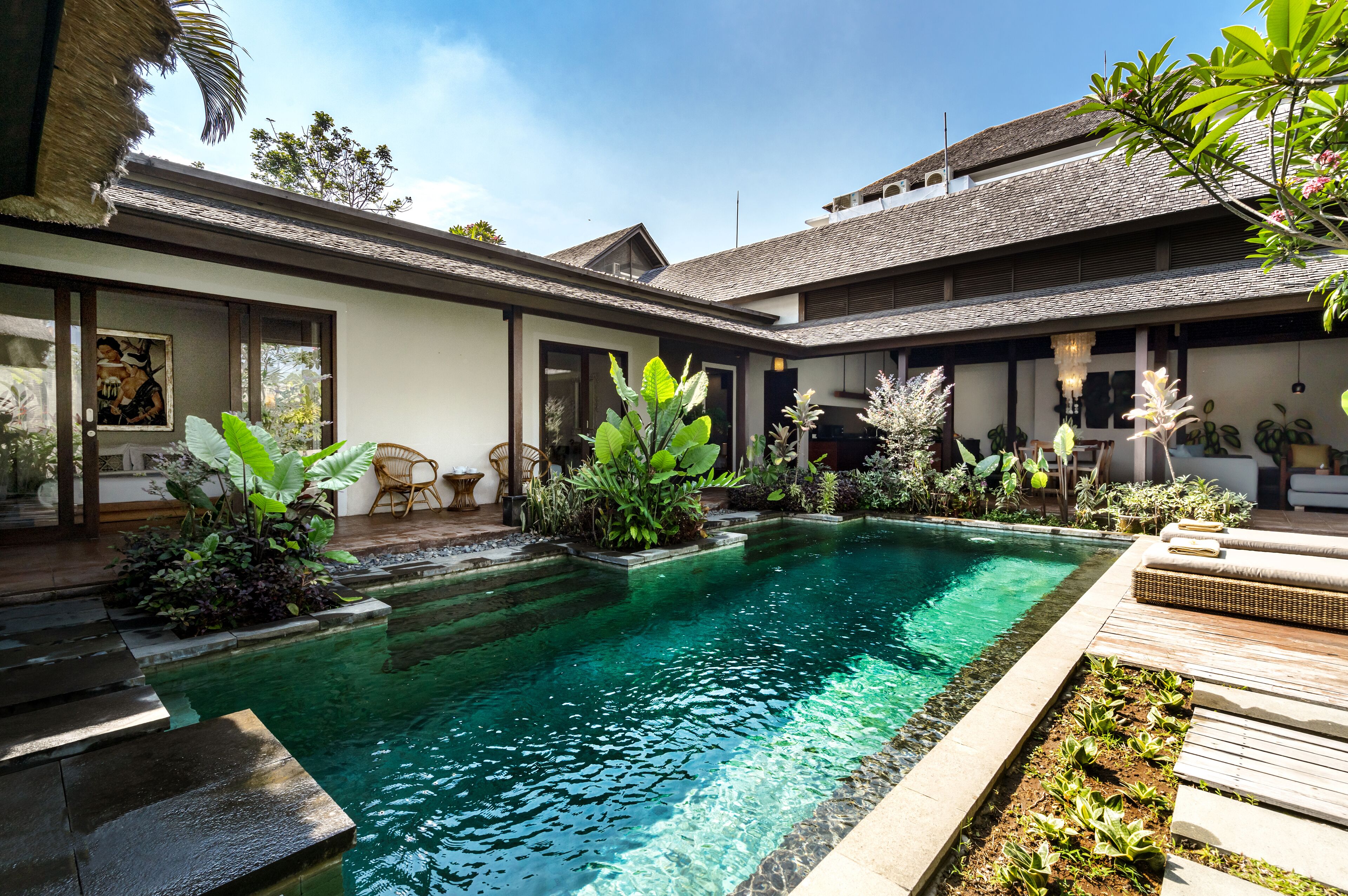 A modern house with a swimming pool, surrounded by lush greenery and outdoor furniture.