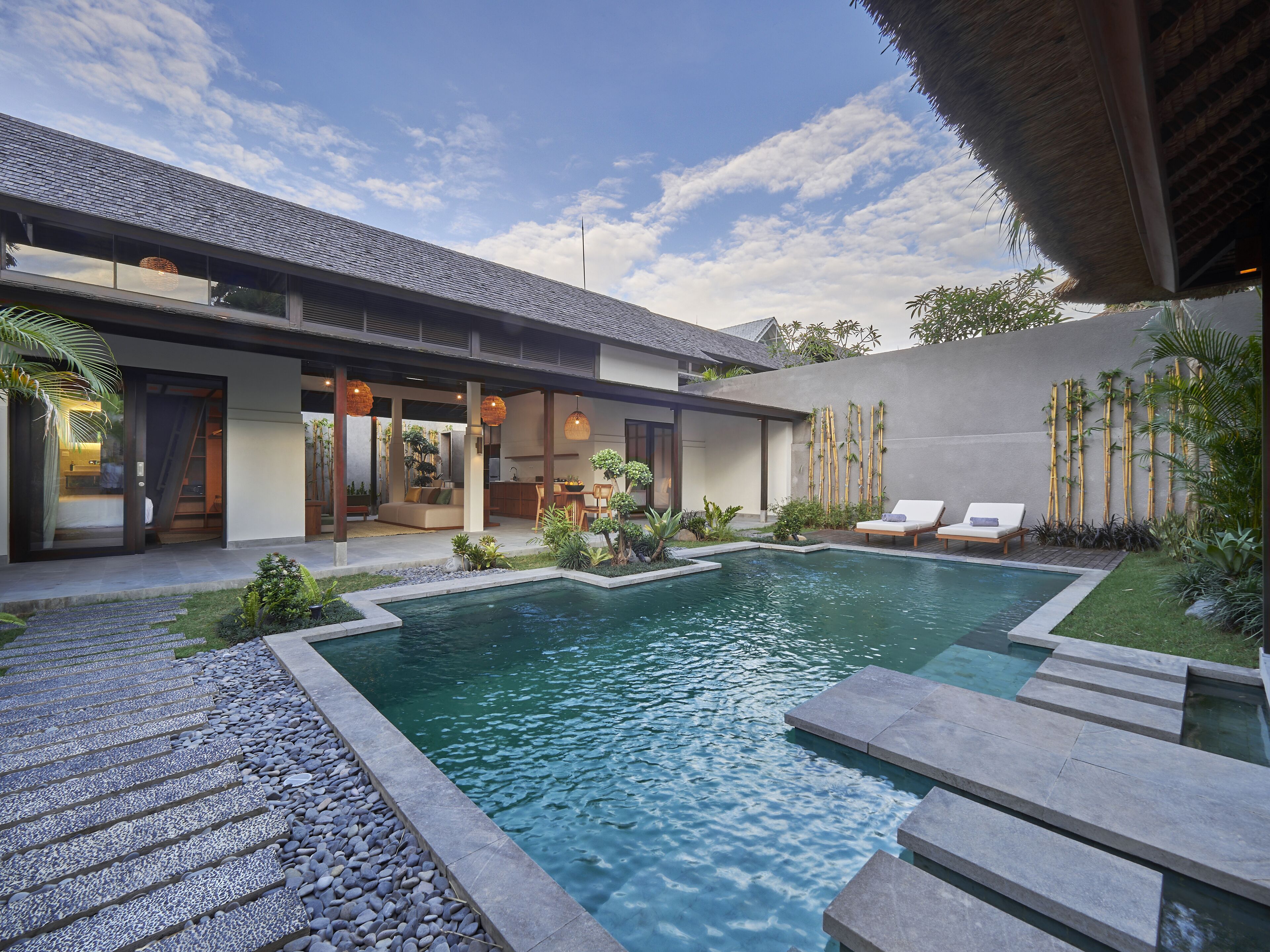 A modern house with a swimming pool, outdoor seating, and a covered patio area.
