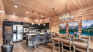 A modern kitchen with wooden walls, stainless steel appliances, and a dining area with wooden furniture.