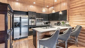 A modern kitchen with wooden walls, stainless steel appliances, and a central island with bar seating.