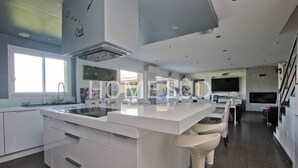 A modern kitchen with a central island, bar stools, a built-in oven, and a large window providing natural light. - Modern 4 bedroom villa with jacuzzi  et  private pool - 25 km from Cannes (SPERACEDES)