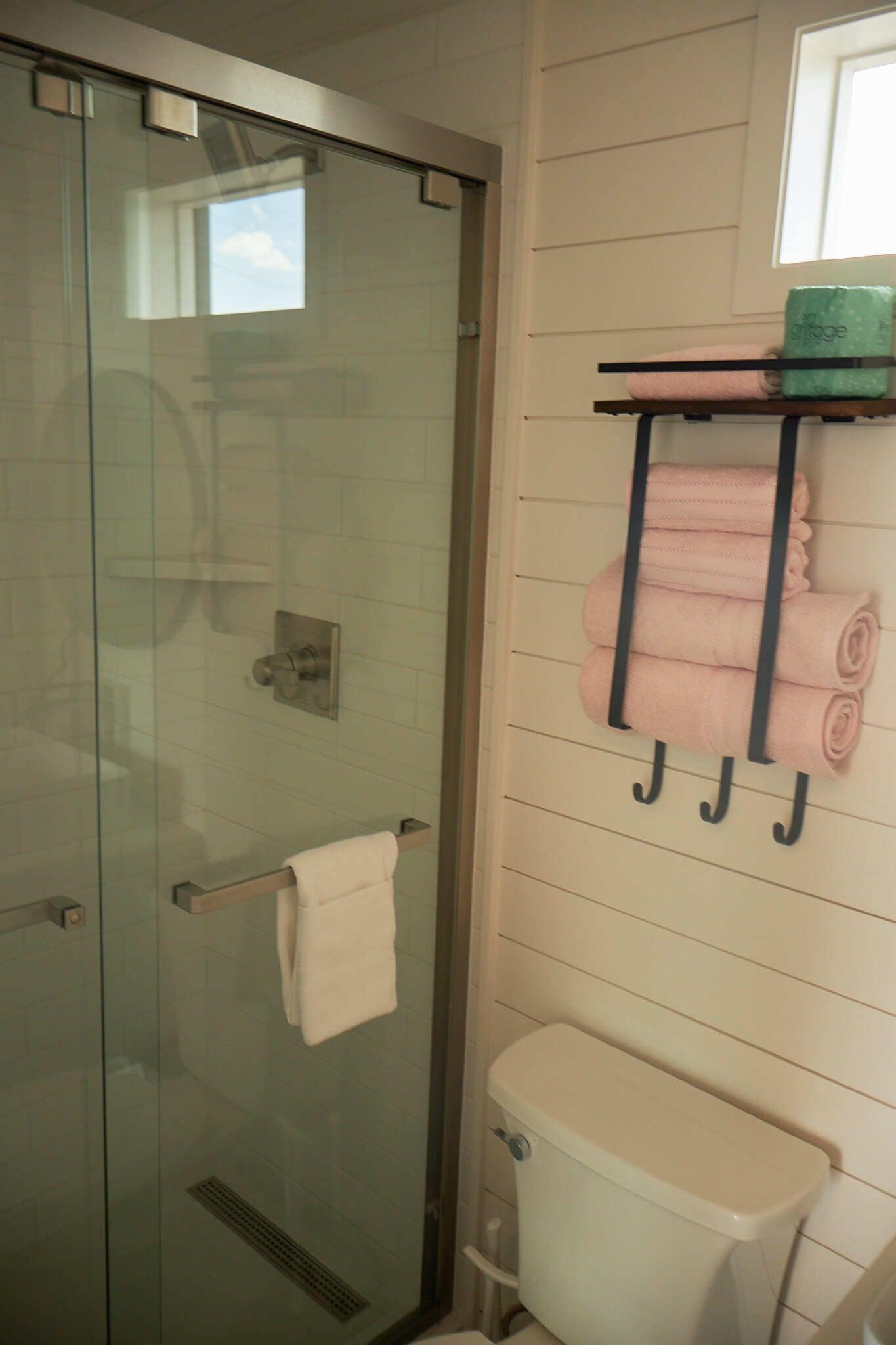 Une salle de bain avec une douche à parois de verre, des toilettes et un porte-serviettes avec des serviettes pliées.
