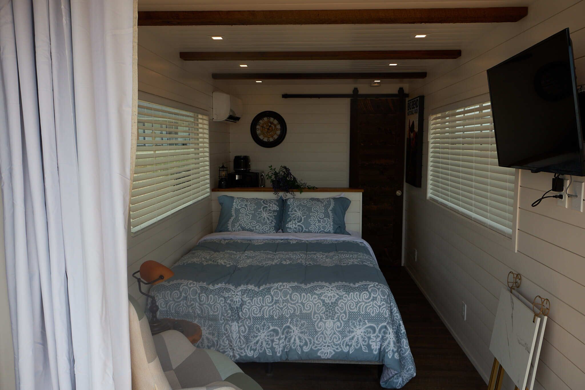 A compact bedroom with a bed, a TV, and a small kitchenette.