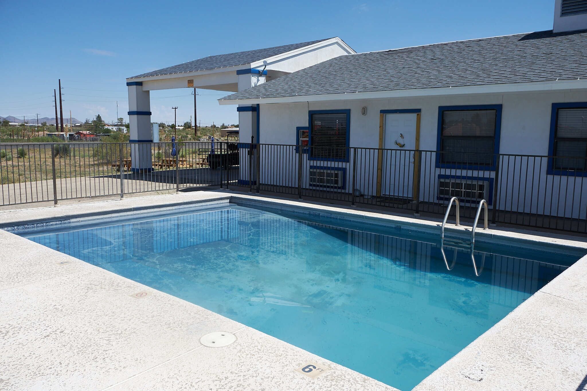 A swimming pool adjacent to a building with a covered patio area.