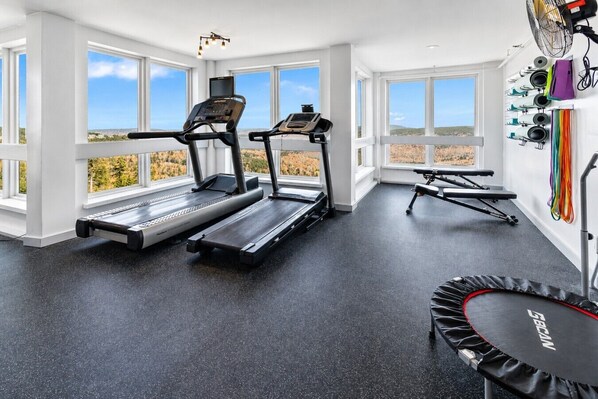 Une salle de sport équipée de tapis de course, d’un vélo d’appartement et d’un trampoline.