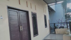 A building with two dark wooden doors, a small window, and a tiled floor. - Hotel O Nany Ayahanda Syariah (Medan)