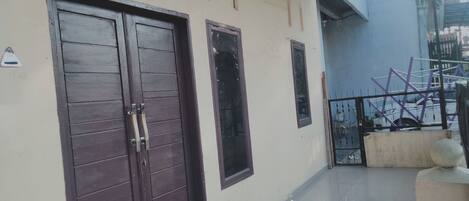 A building with two dark wooden doors, a small window, and a tiled floor.