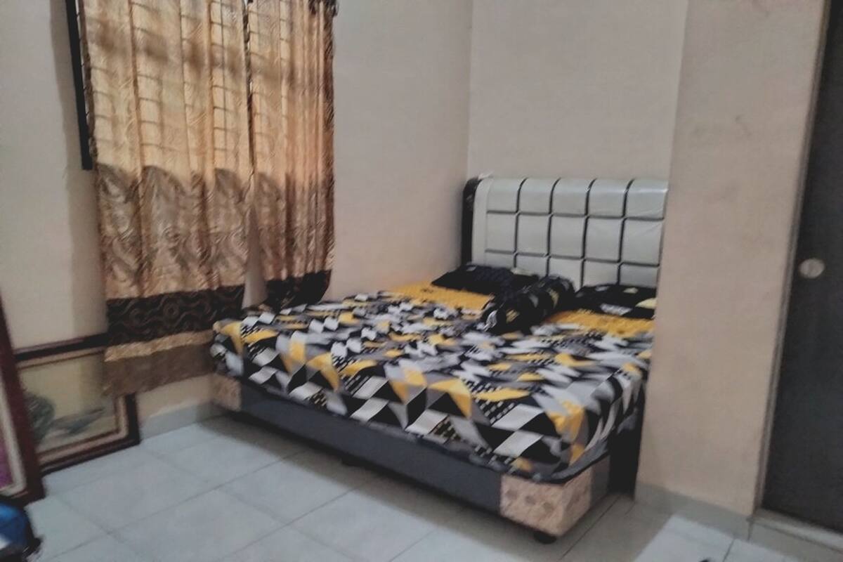 A bedroom with a bed, curtains, and a tiled floor.