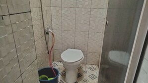 A small bathroom with a toilet, a shower hose, and a bucket. - Hotel O Nany Ayahanda Syariah (Medan)